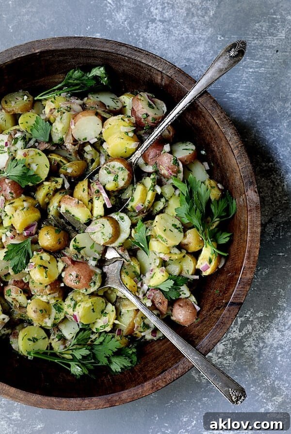French-Style Potato Salad - Overhead hero shot of salad in wood bowl with serving utensils