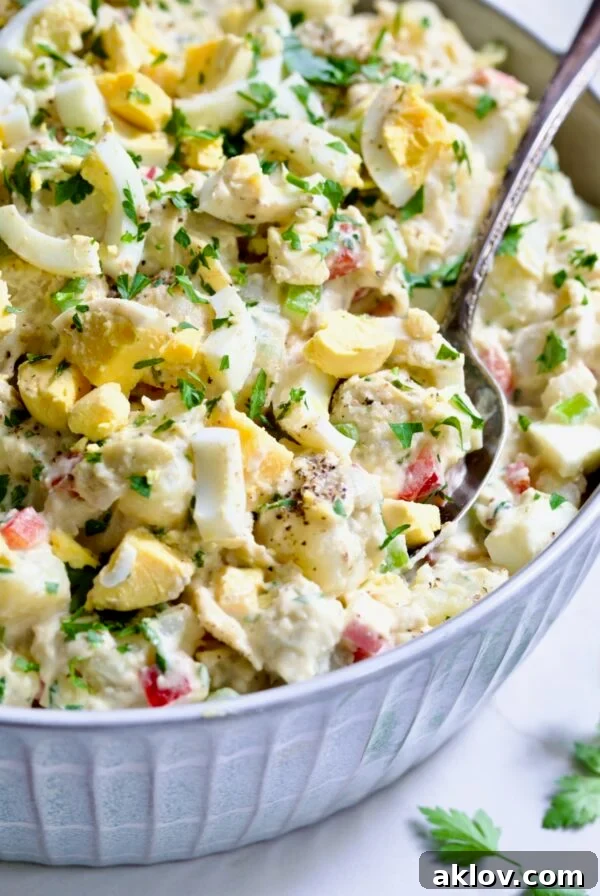 Potato Salad with Horseradish Dressing in light blue bowl with serving spoon garnished with parsley.