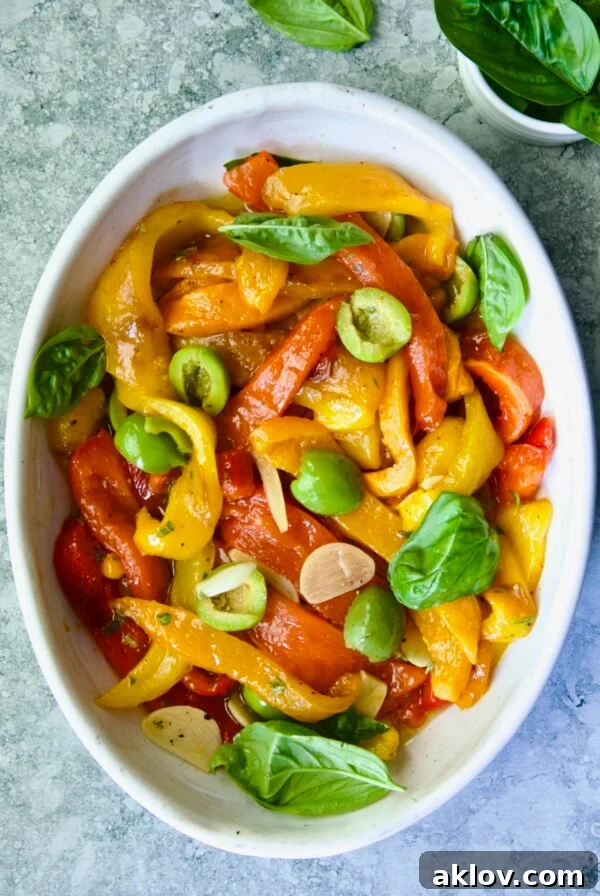 Roasted Pepper Salad in white oval serving bowl garnished with fresh basil leaves.
