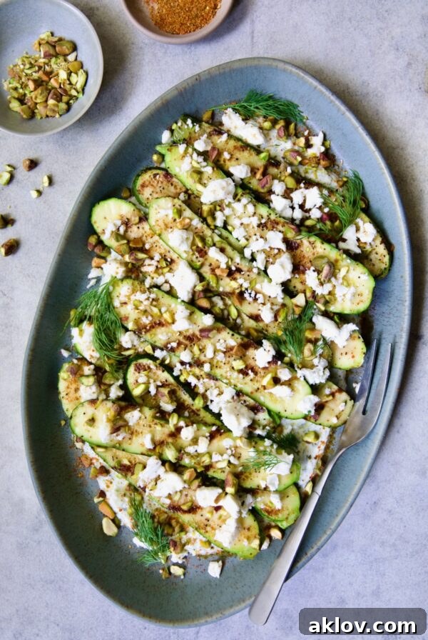 Mediterranean Grilled Zucchini with Dill Yogurt and Feta on blue platter garnished with pistachios and fresh dill sprigs.