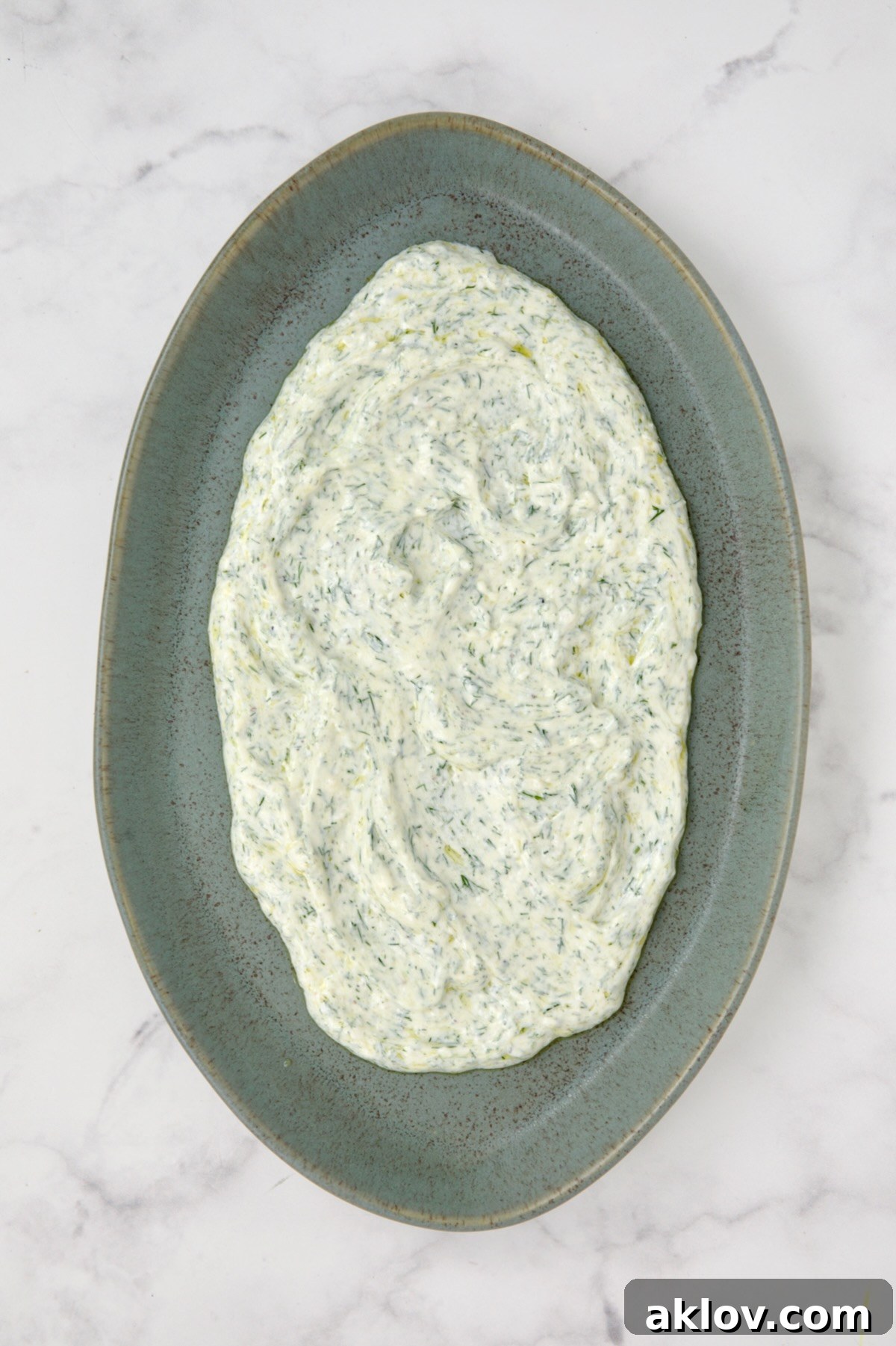 The creamy dill yogurt sauce beautifully spread across a blue serving platter, creating a base for the grilled zucchini.