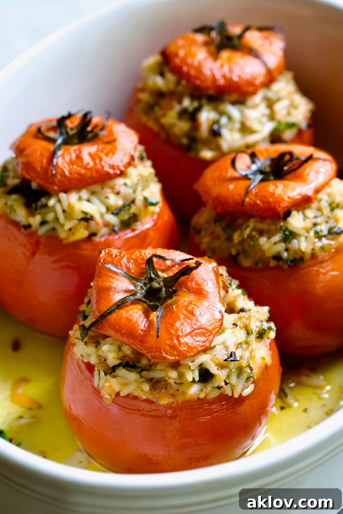 Four Cheesy Rice Stuffed Tomatoes in white baking dish, fresh out of the oven.