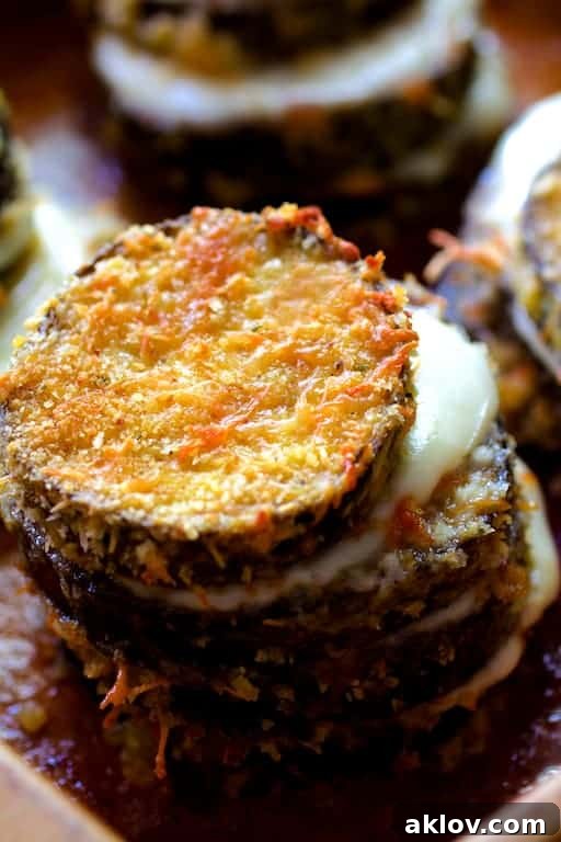 Close-up photo capturing the luscious, melty cheese nestled between layers of crispy eggplant in a stack, ready to be devoured.