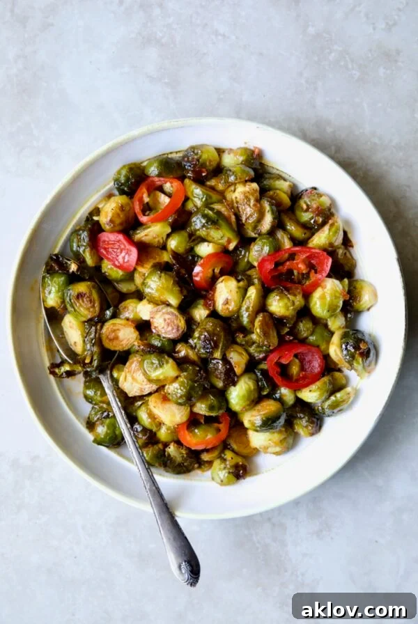 Hot Honey Brussels Sprouts in white serving bowl with serving spoon.