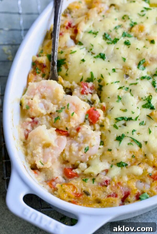 Shrimp and Grits Casserole in an oval white baking dish with a serving spoon, highlighting its creamy texture.