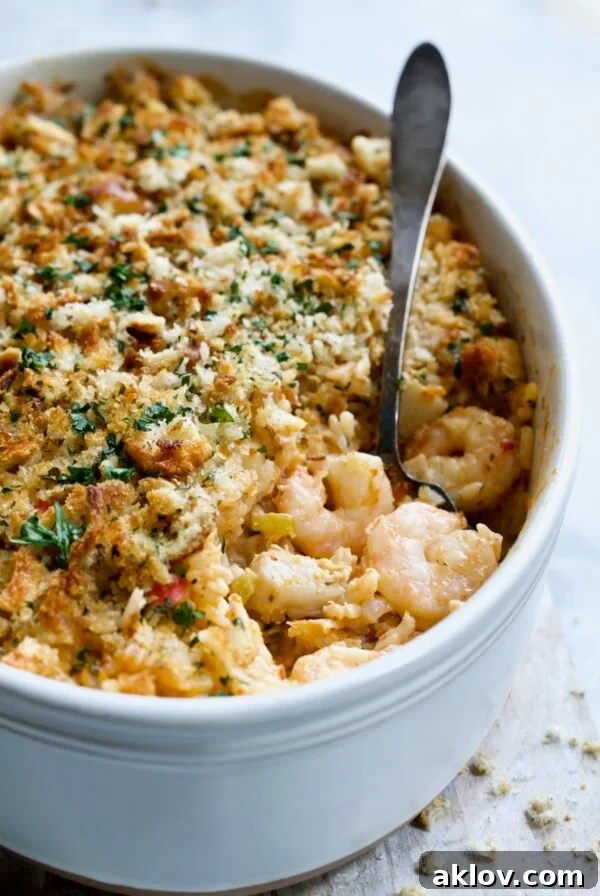 Shrimp and Crab Seafood Casserole in a white baking dish, with a serving spoon scooping up a generous portion of shrimp and crab.