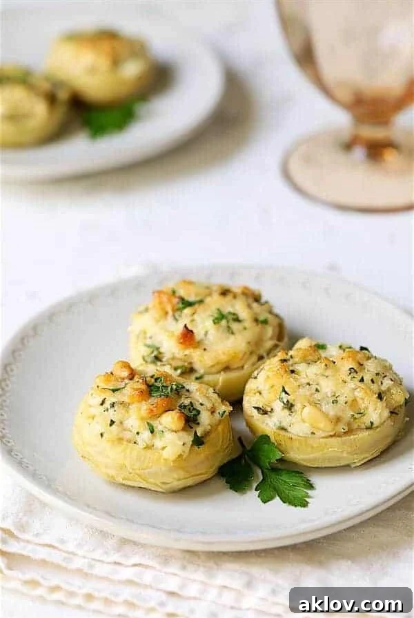 Three Lemon Parmesan Stuffed Artichoke Bottoms elegantly arranged on a white plate, showcasing their golden crust and fresh herbs.