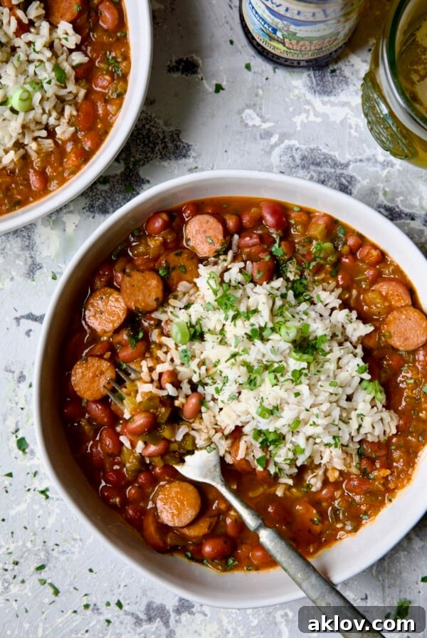 Easy Red Beans and Rice in a white bowl on a light blue background, with a fork scooping out a portion of beans.
