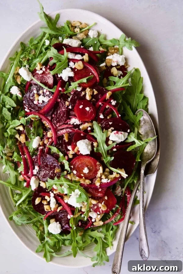 Photo of vibrant Roasted Beet Salad with Walnuts, Goat Cheese, and Honey Balsamic Dressing on a white oval platter.