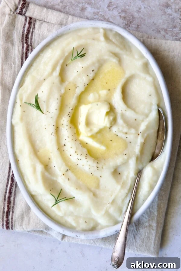 Creamy Turnip Potato Puree served in a white oval bowl with a serving spoon resting on a napkin with a red stripe.