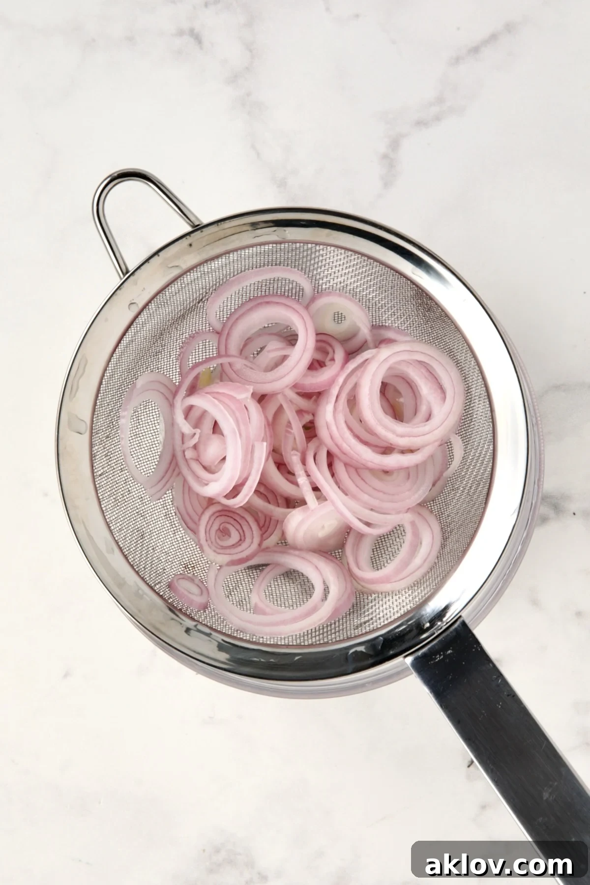 Shallot rings in stainless steel sieve.