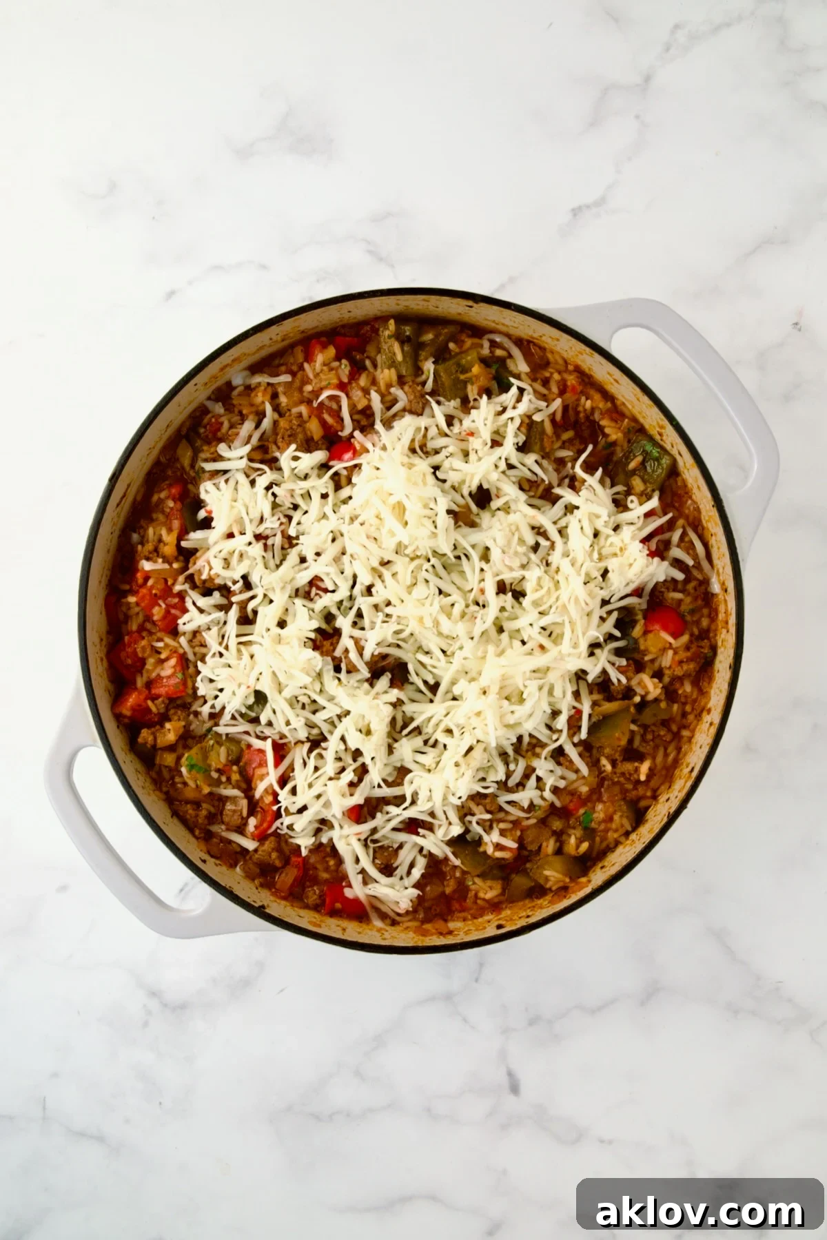 Shredded cheese being stirred into the hot Unstuffed Peppers Skillet mixture.