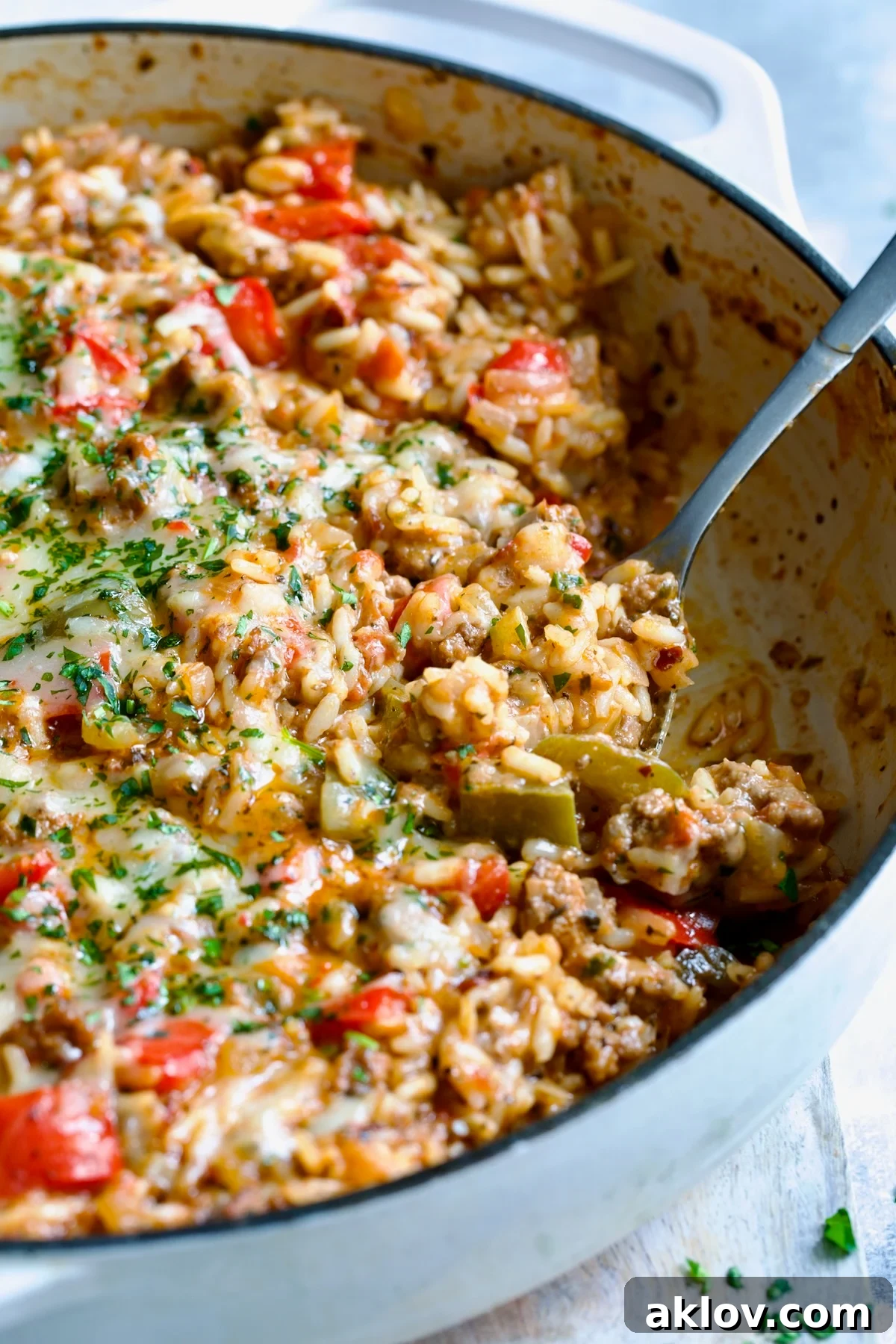 Close-up of Unstuffed Peppers Skillet showing melted cheese and vibrant ingredients in a white enamel cast iron skillet.