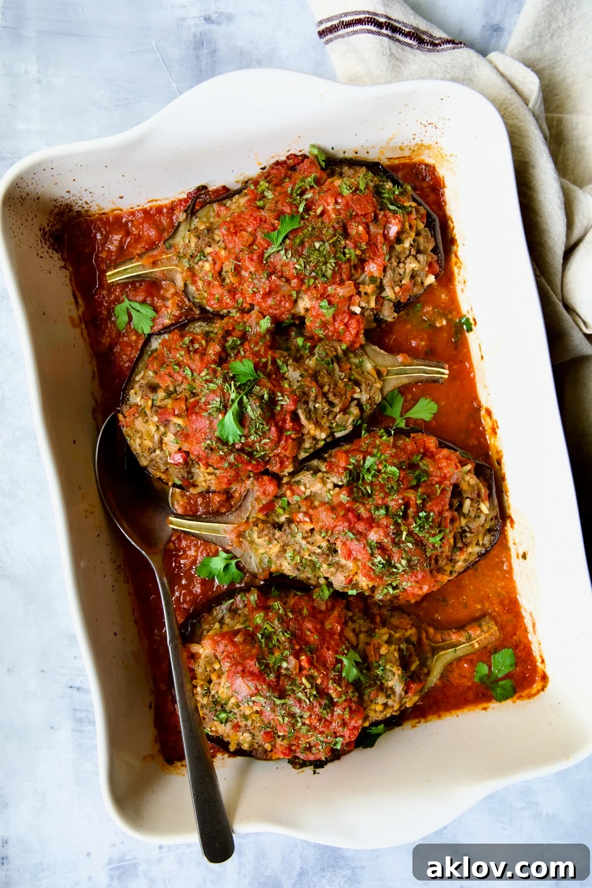 Four baked Stuffed Eggplant halves in white rectangular baking dish.
