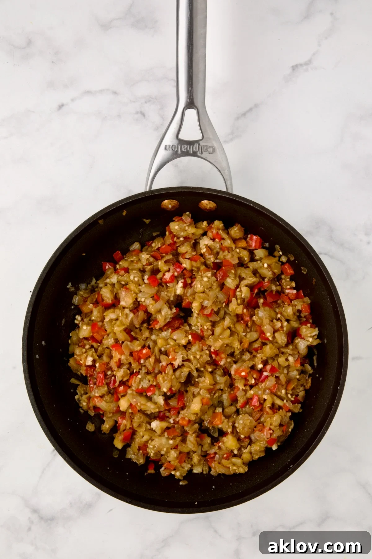 Cooked eggplant flesh, onions and red bell pepper in nonstick saute pan.