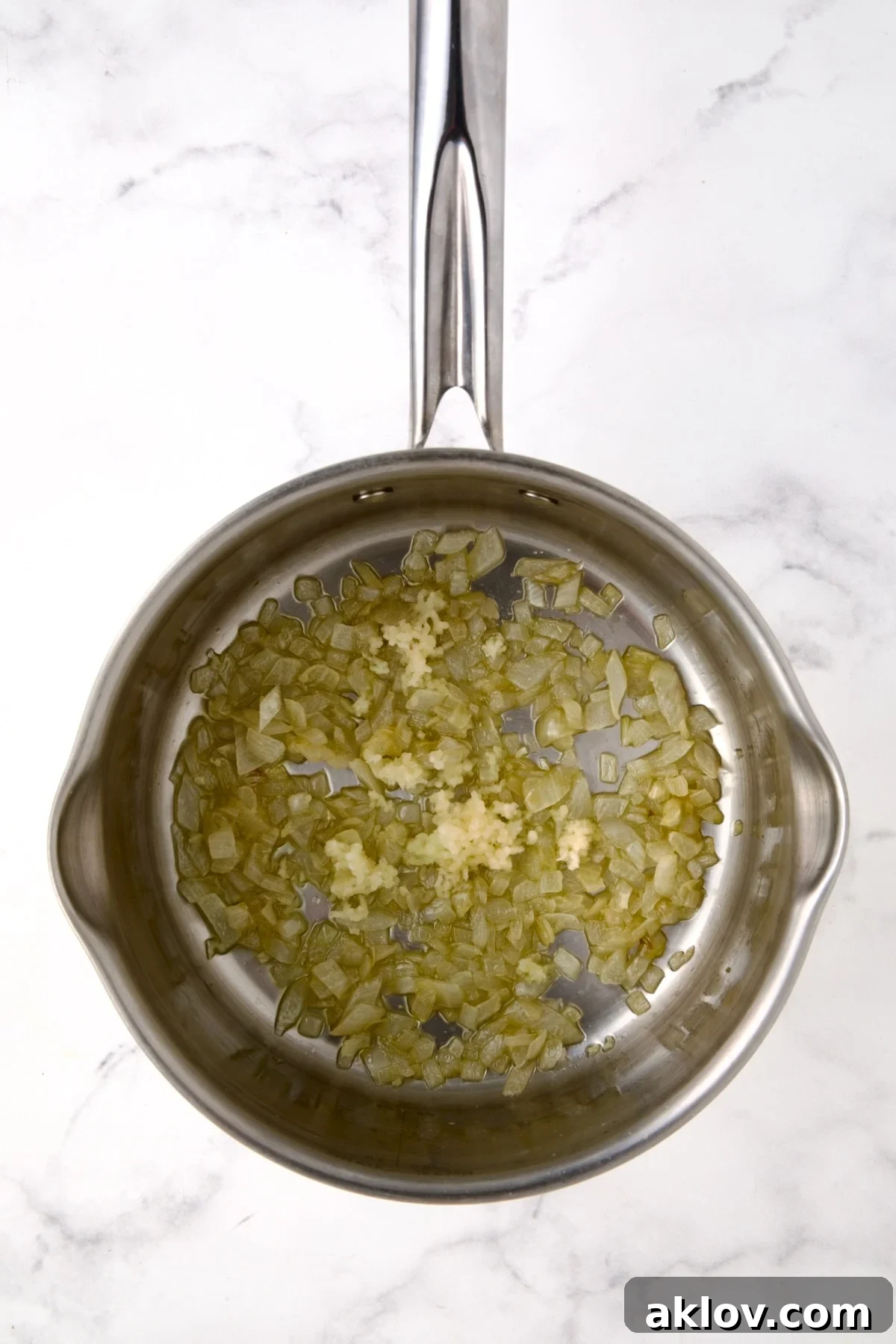 Cooked onions and garlic in stainless steel saucepan.