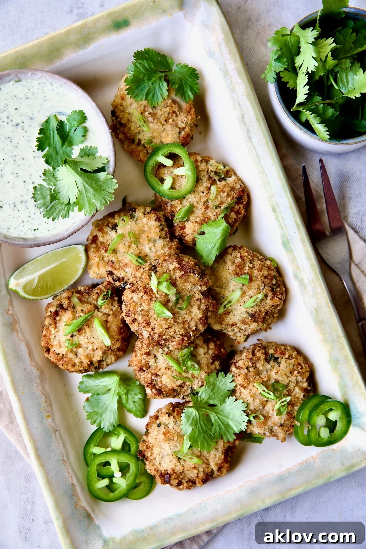 Thai Green Curry Shrimp Cakes on rectangular platter garnished with jalapeno slices and cilantro leaves.