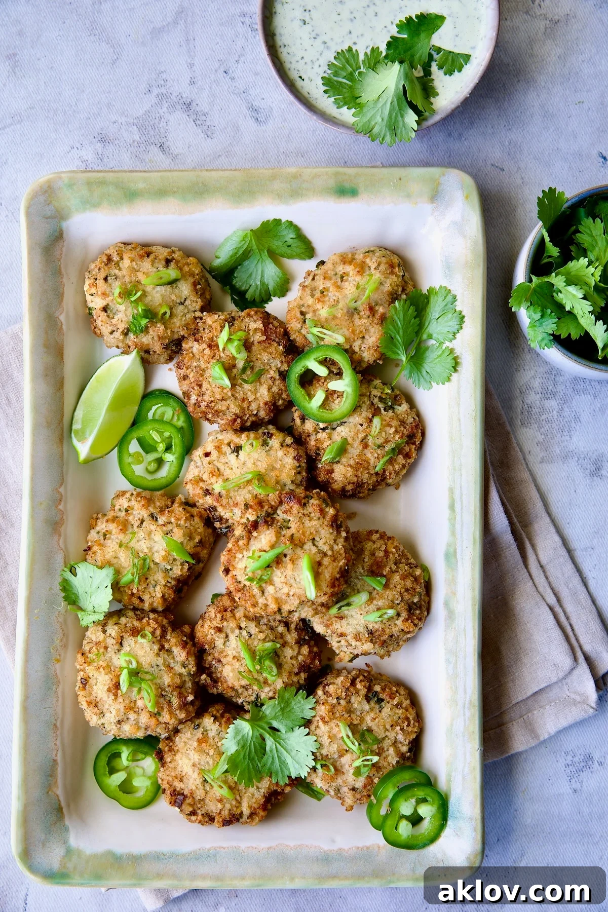 Thai Green Curry Shrimp Cakes on rectangular platter garnished with jalapeno slices and cilantro leaves.