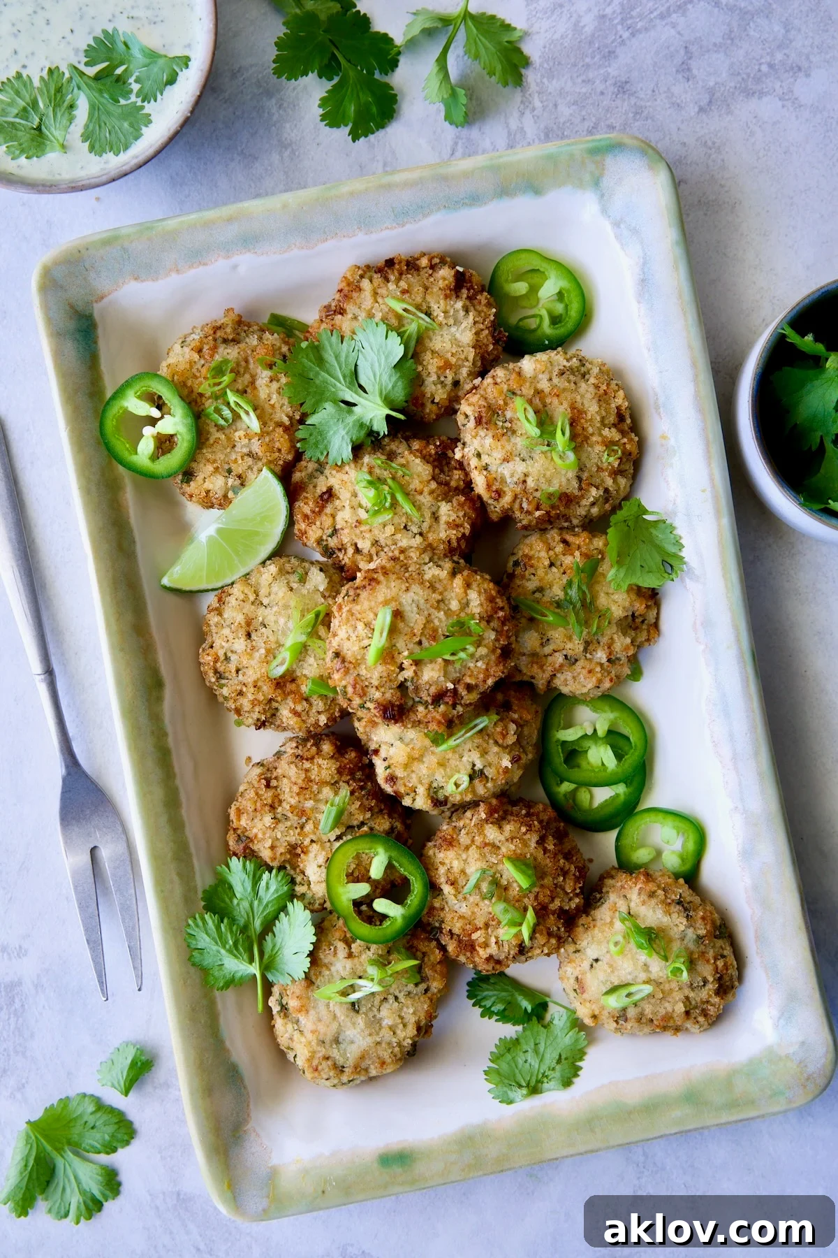 Thai Green Curry Shrimp Cakes on rectangular platter garnished with jalapeno slices and cilantro leaves.