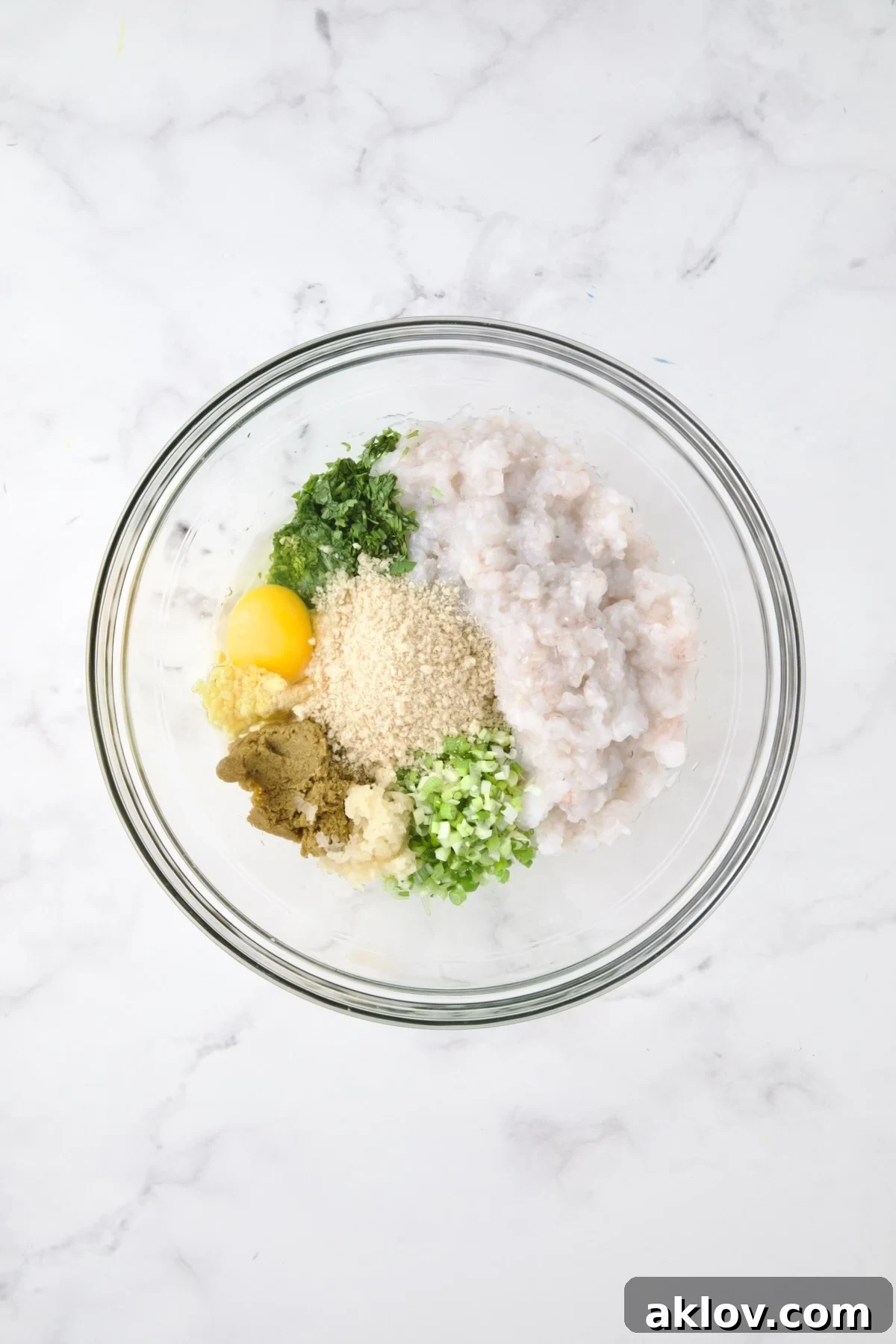 Ingredients for shrimp cakes in glass bowl before being combined.