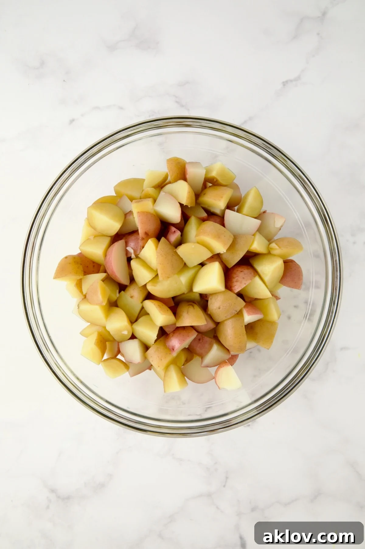 Cubed cooked red and yellow potatoes in glass bowl.