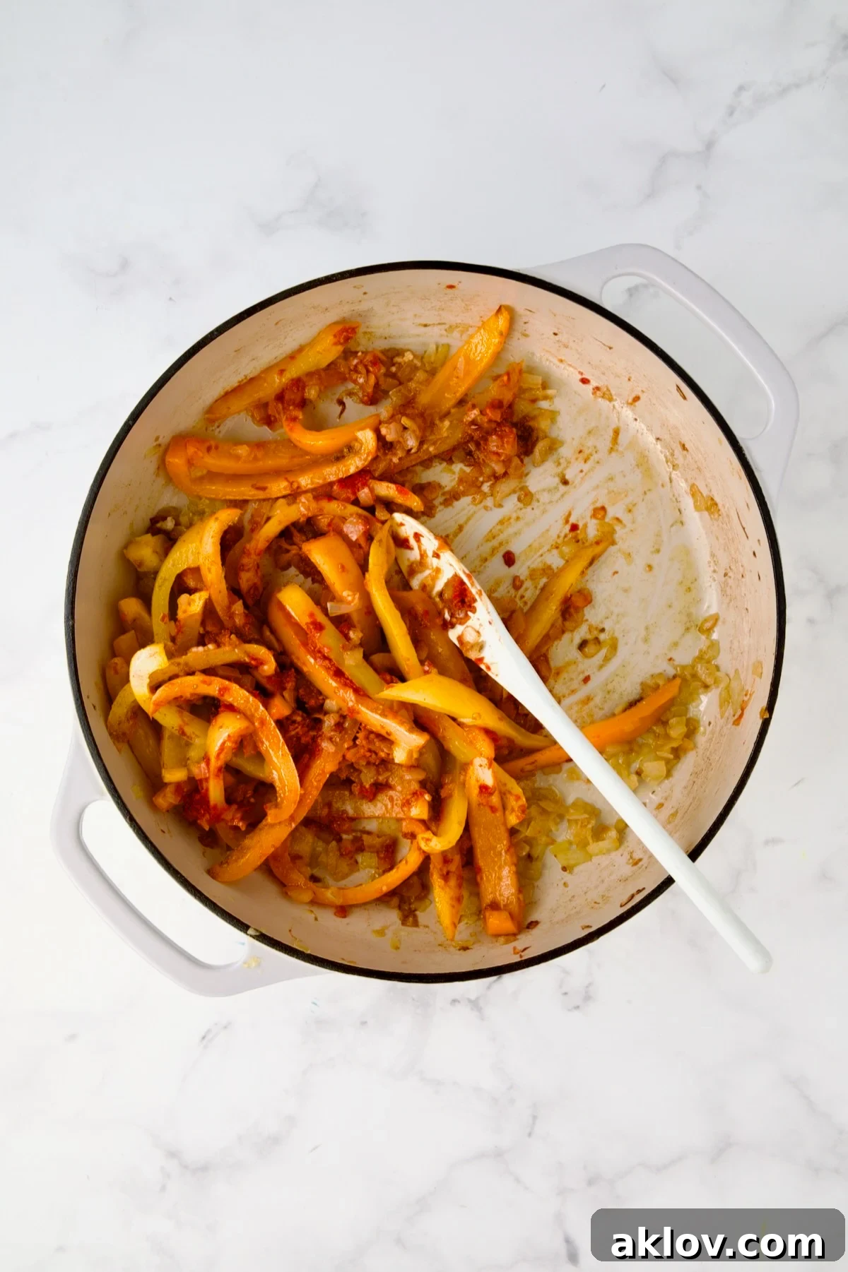 Stirring the spices into the onions and peppers until fragrant.