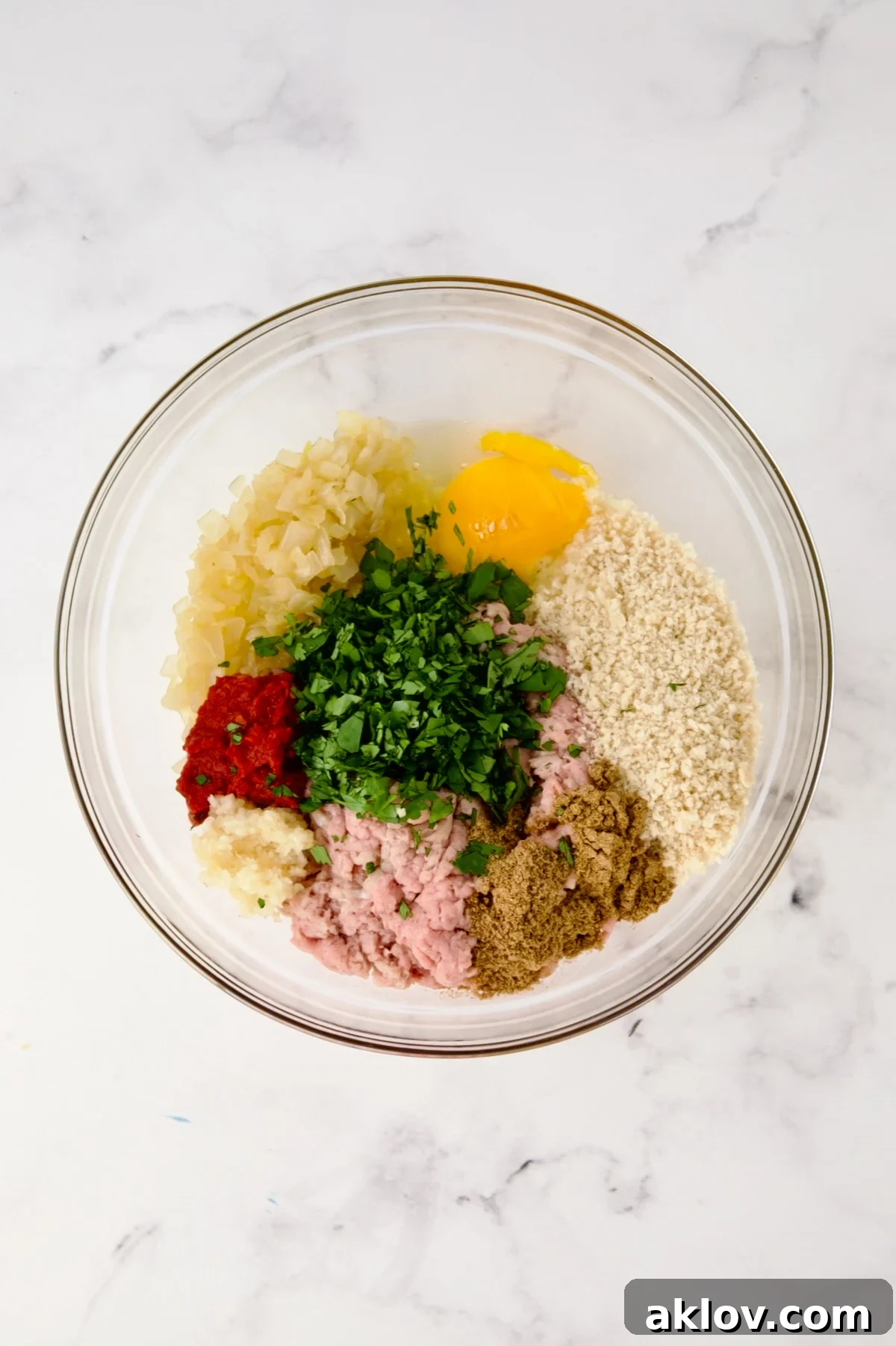 Meatball ingredients in a glass bowl, ready to be mixed.