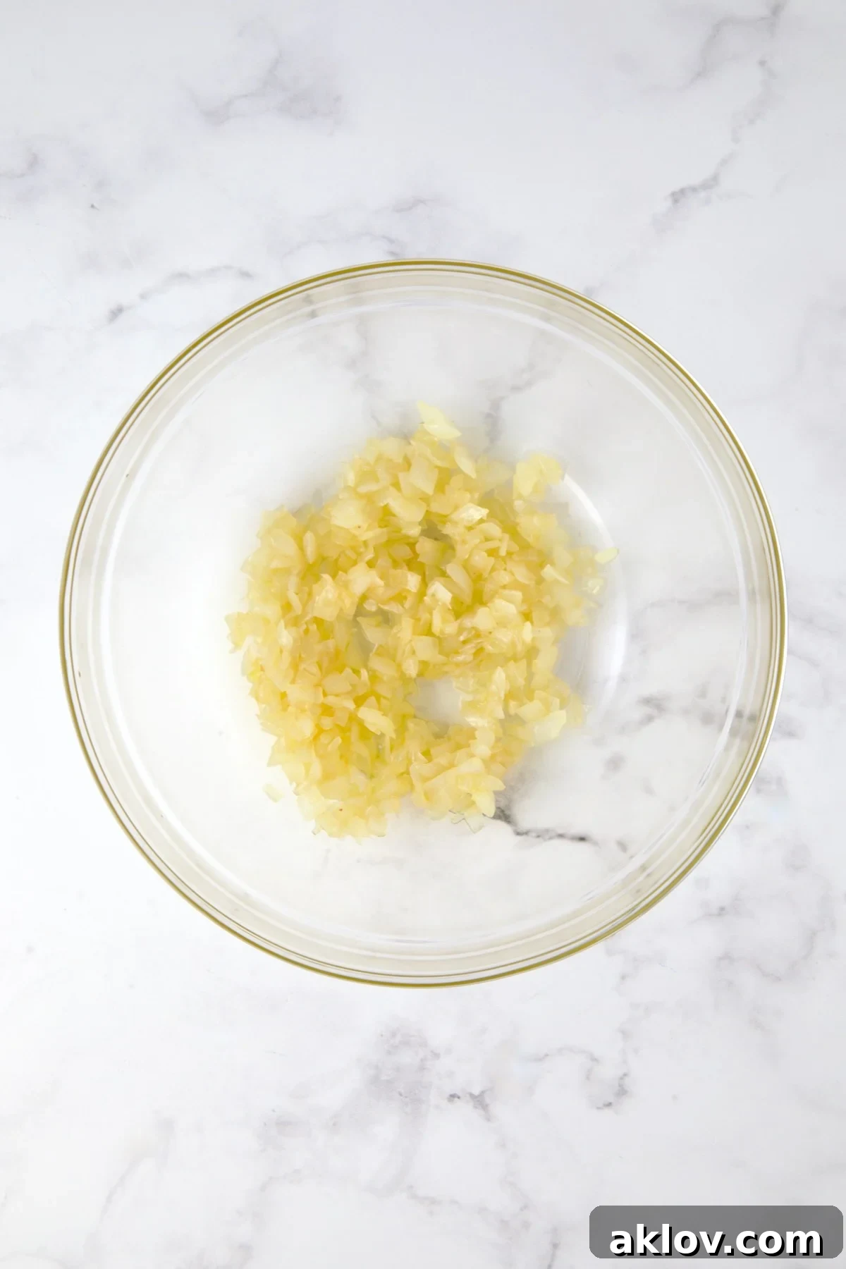 Transferring a portion of the cooked onions to a glass mixing bowl.