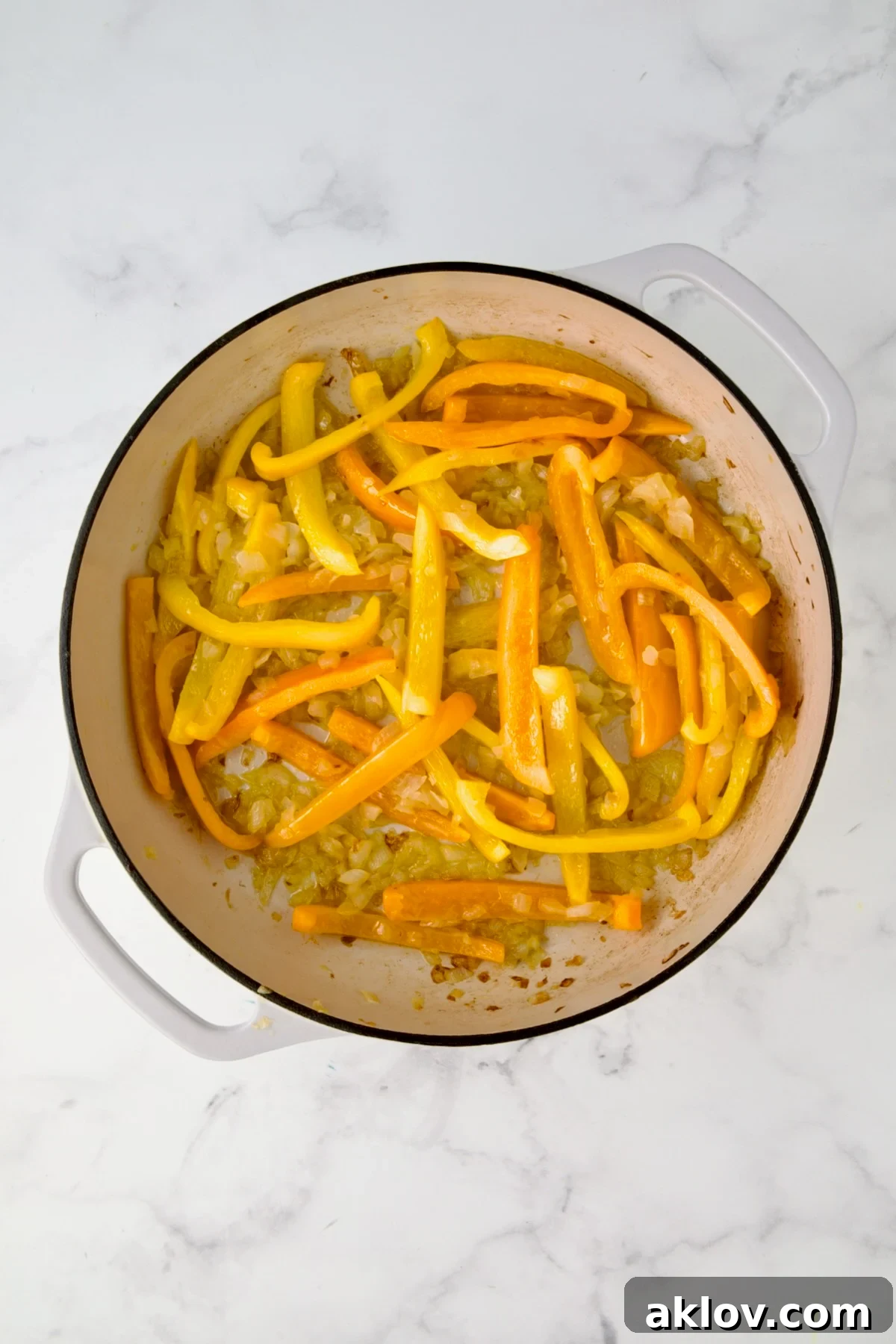 Adding sliced bell peppers to the onions in the skillet.