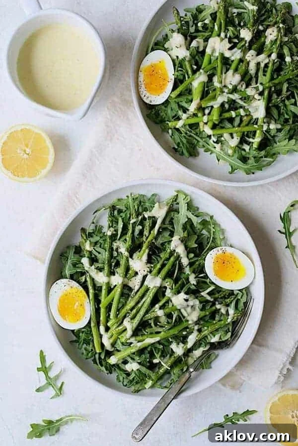 Two servings of Arugula, Egg and Asparagus Salad with Creamy Lemon Vinaigrette in white bowls.