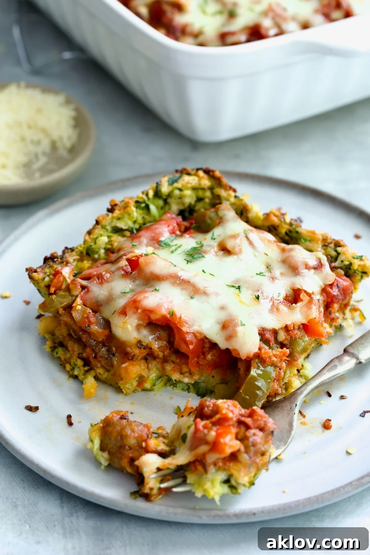 Piece of Zucchini Pizza Casserole on small plate with a piece on a fork.