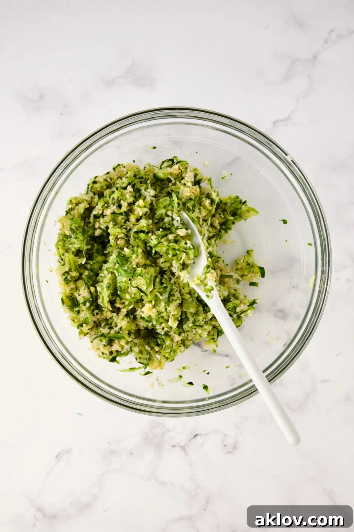 Ingredients for the zucchini crust in glass bowl after being mixed together.