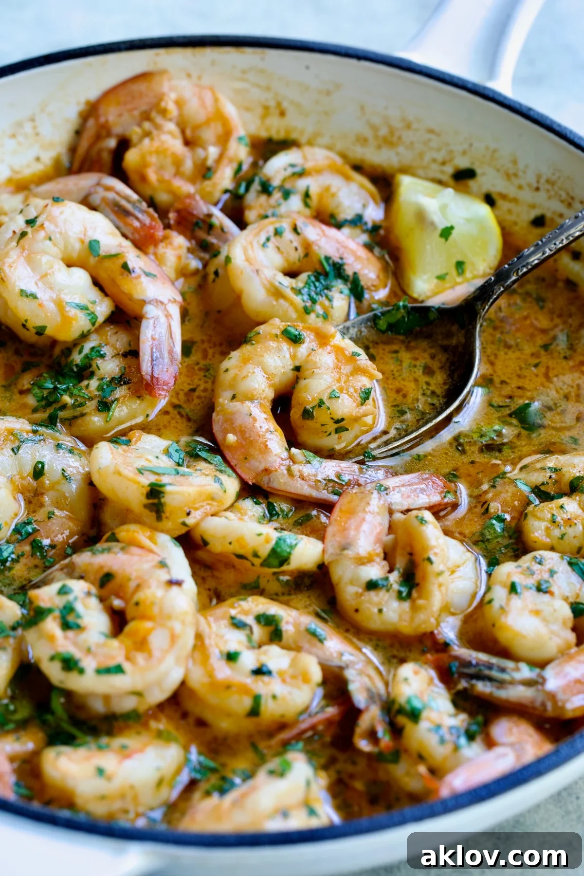 Cajun Butter Shrimp in skillet with spoon lifting a shrimp.