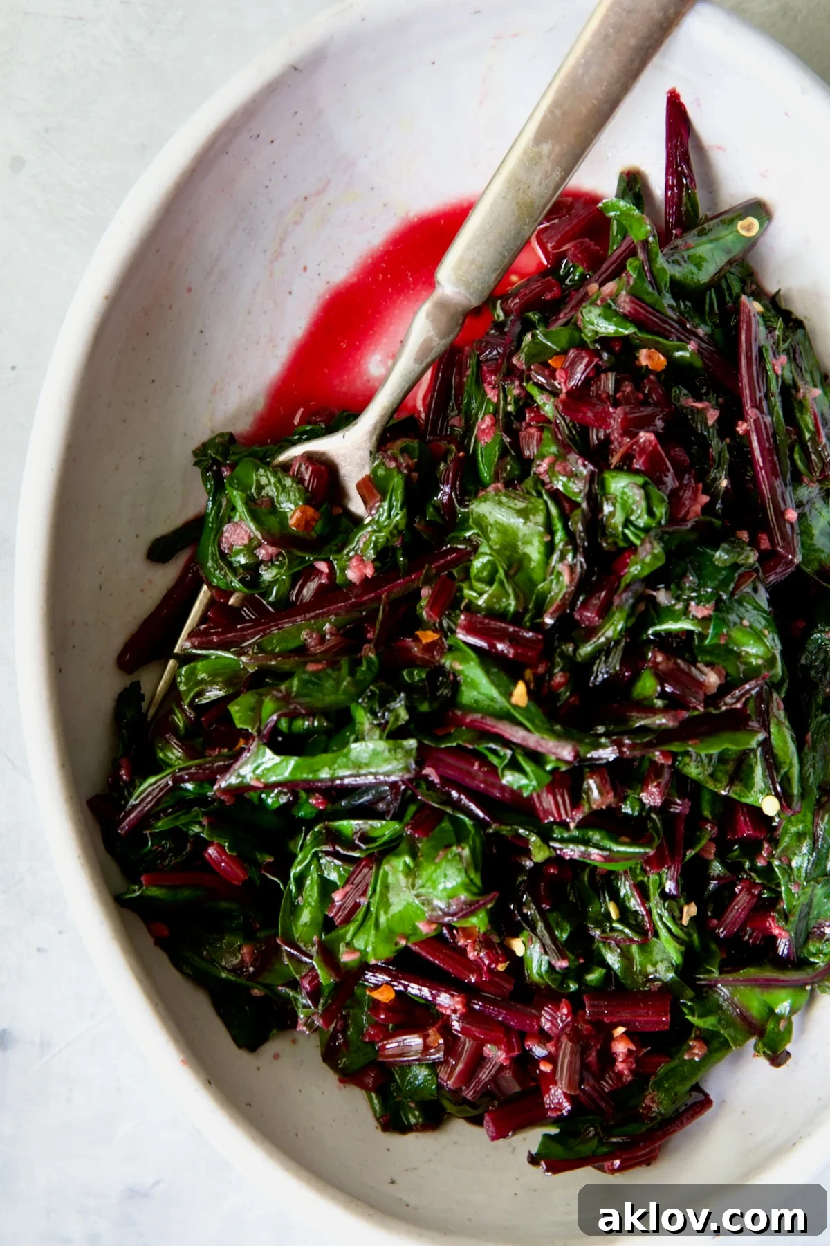Sauteed Beet Greens in oval white serving bowl with fork.