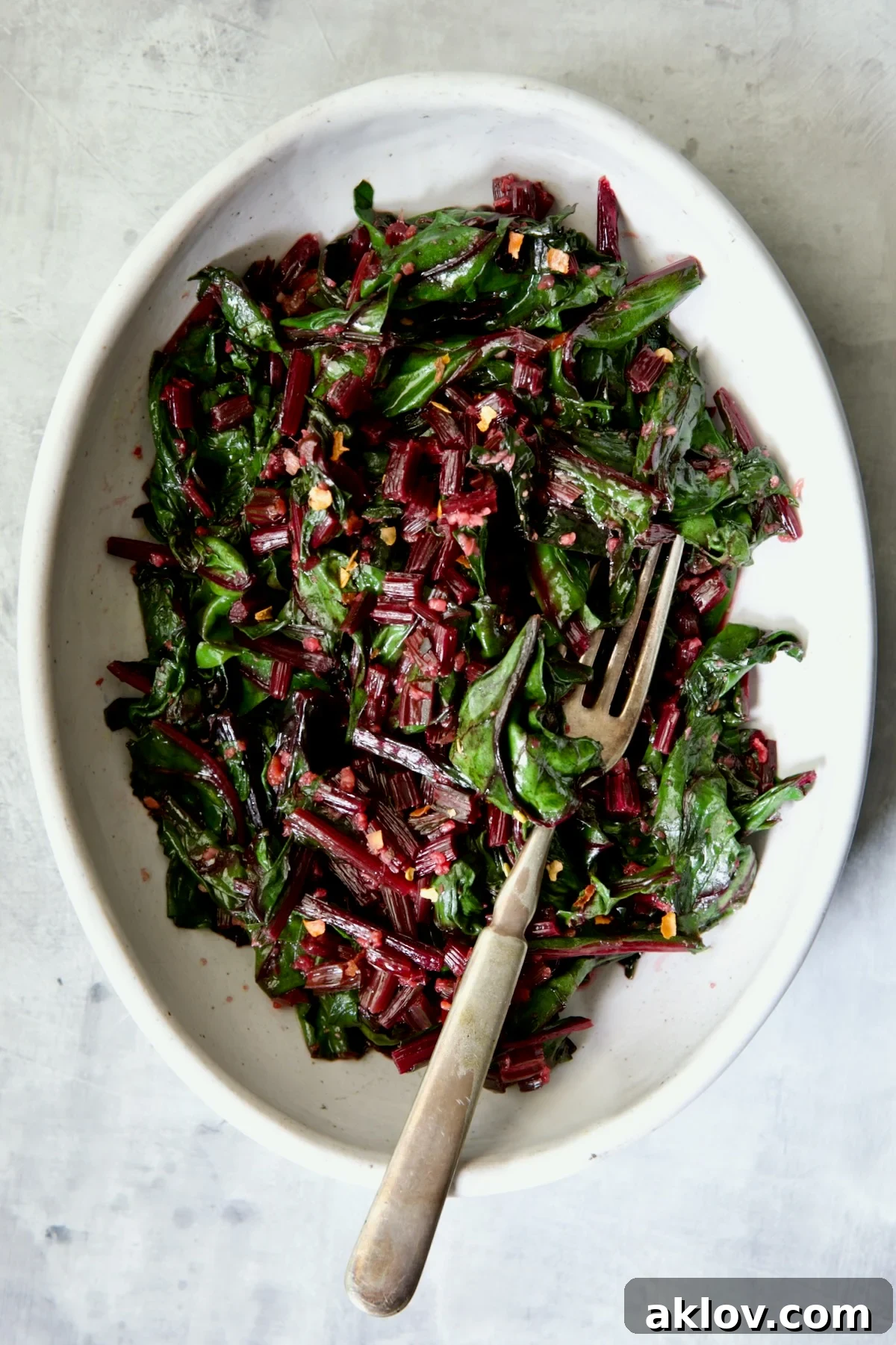 Sauteed Beet Greens in oval white serving bowl with fork.