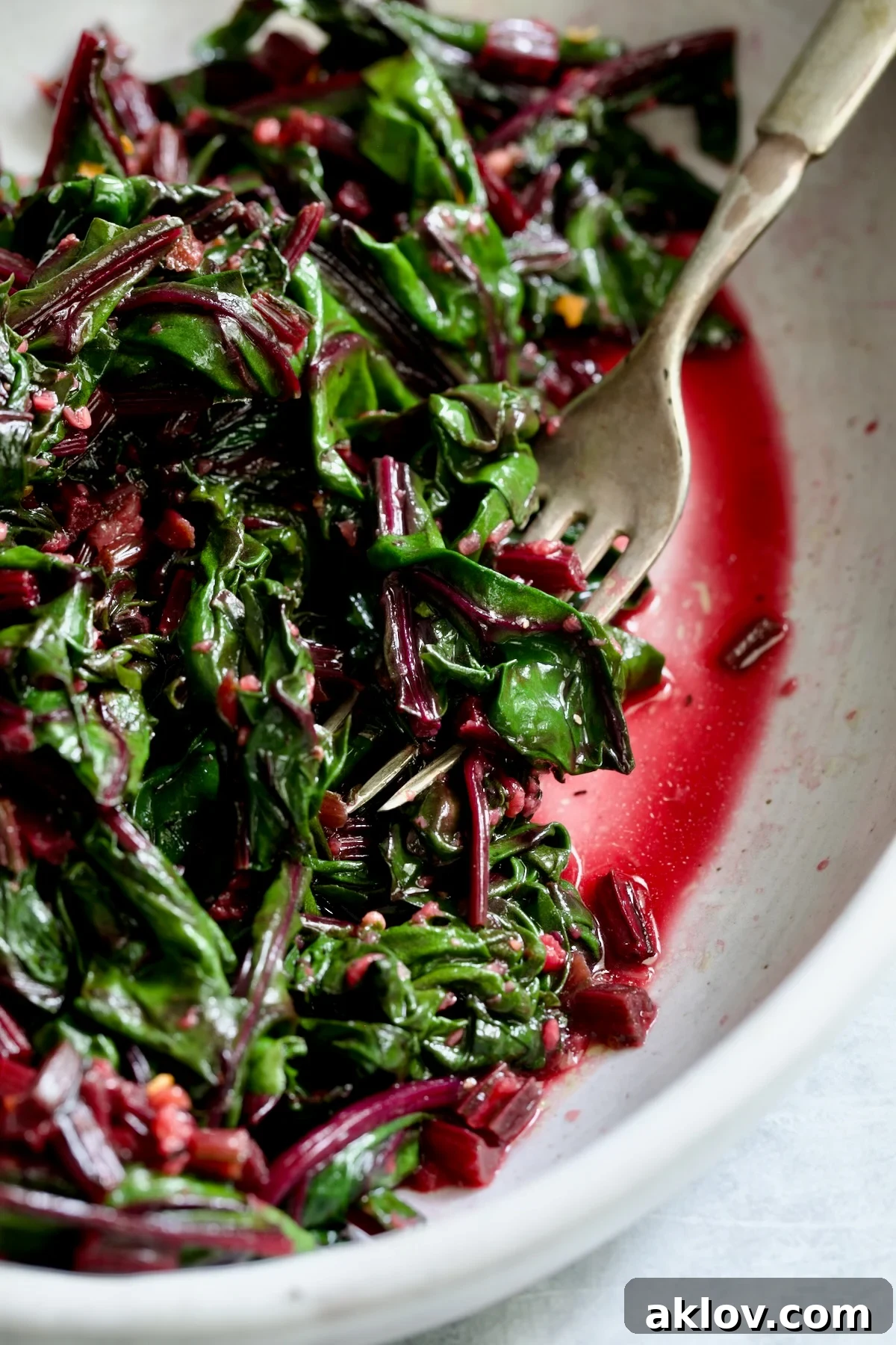 Sauteed Beet Greens in oval white serving bowl with fork.