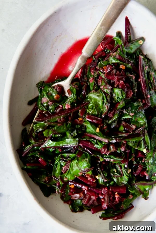 Sauteed Beet Greens in oval white serving bowl with fork.