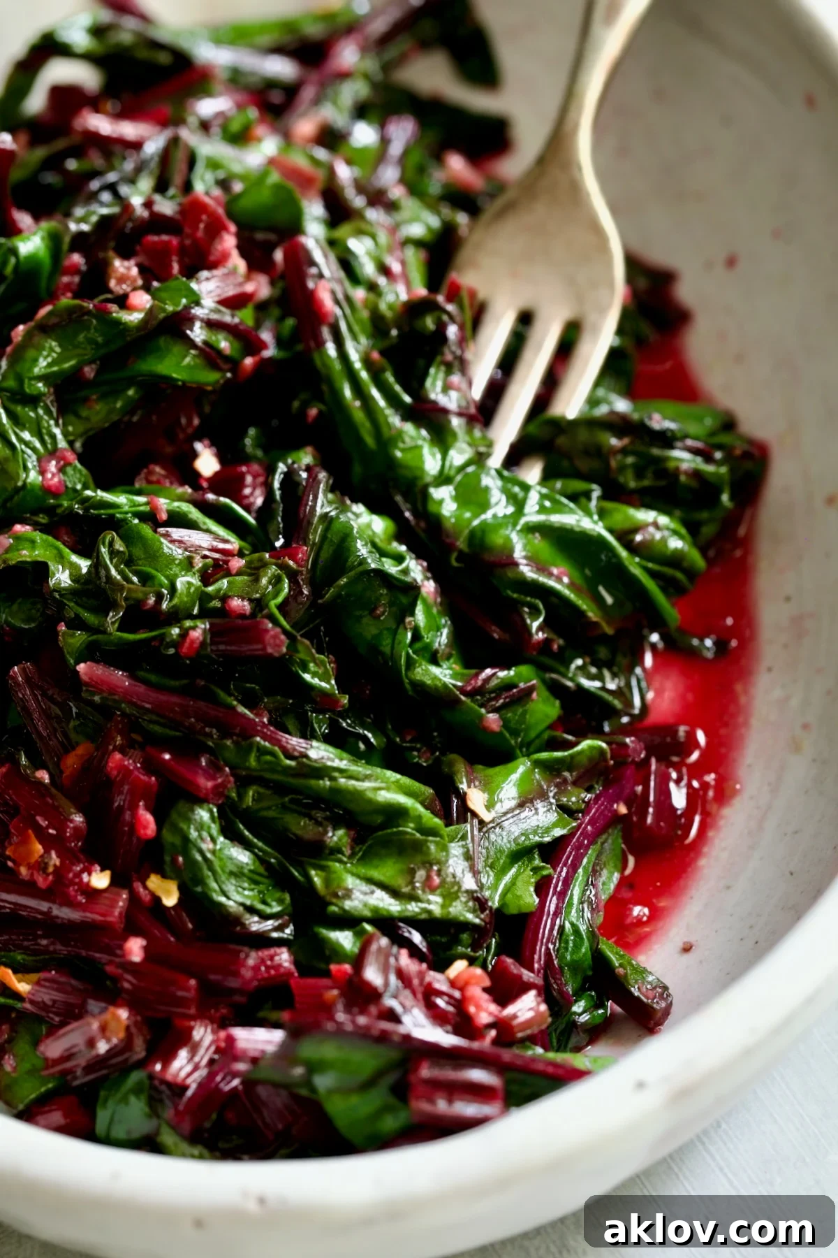 Sauteed Beet Greens in oval white serving bowl with fork.
