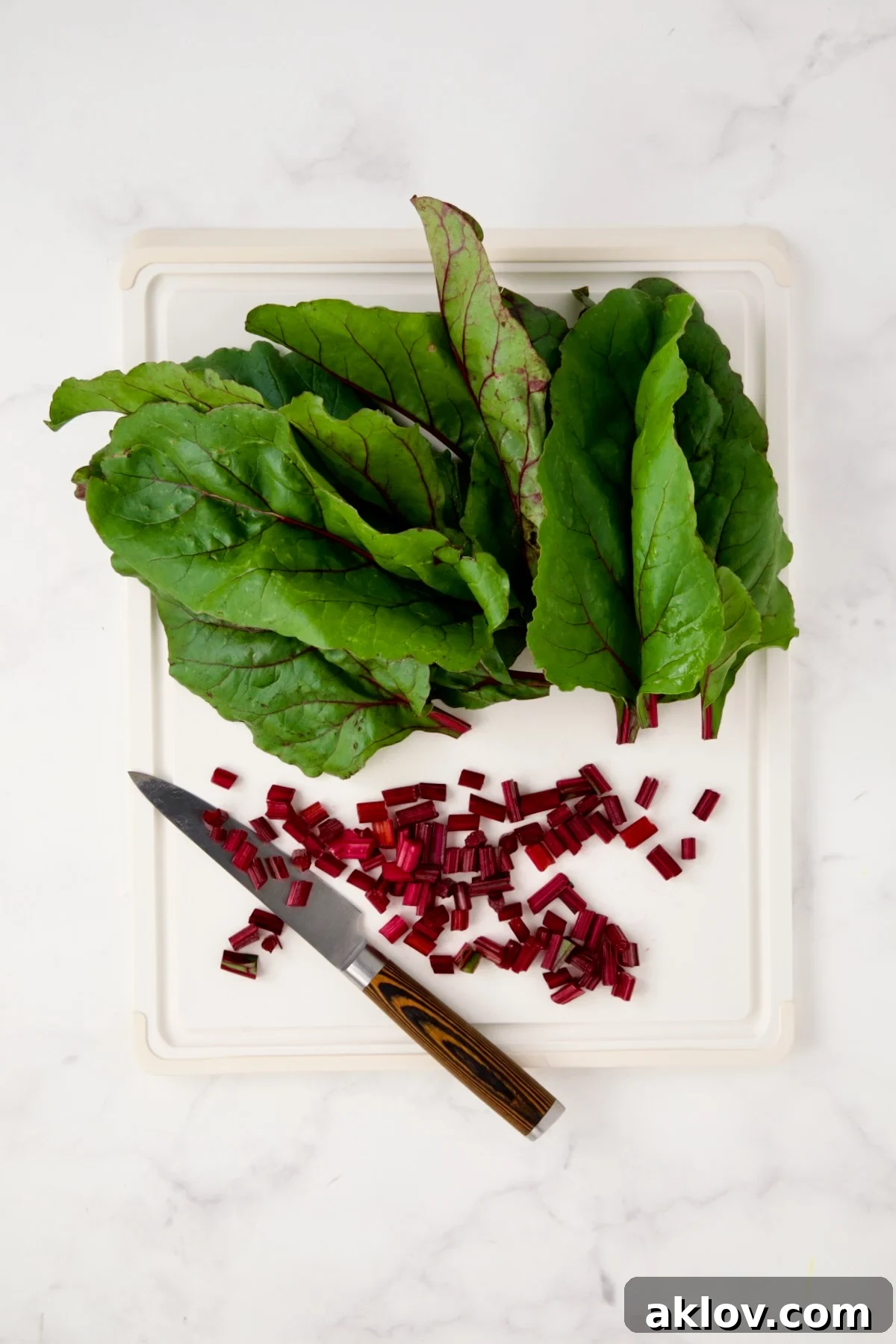 Beet greens and chopped stems on white cutting board.