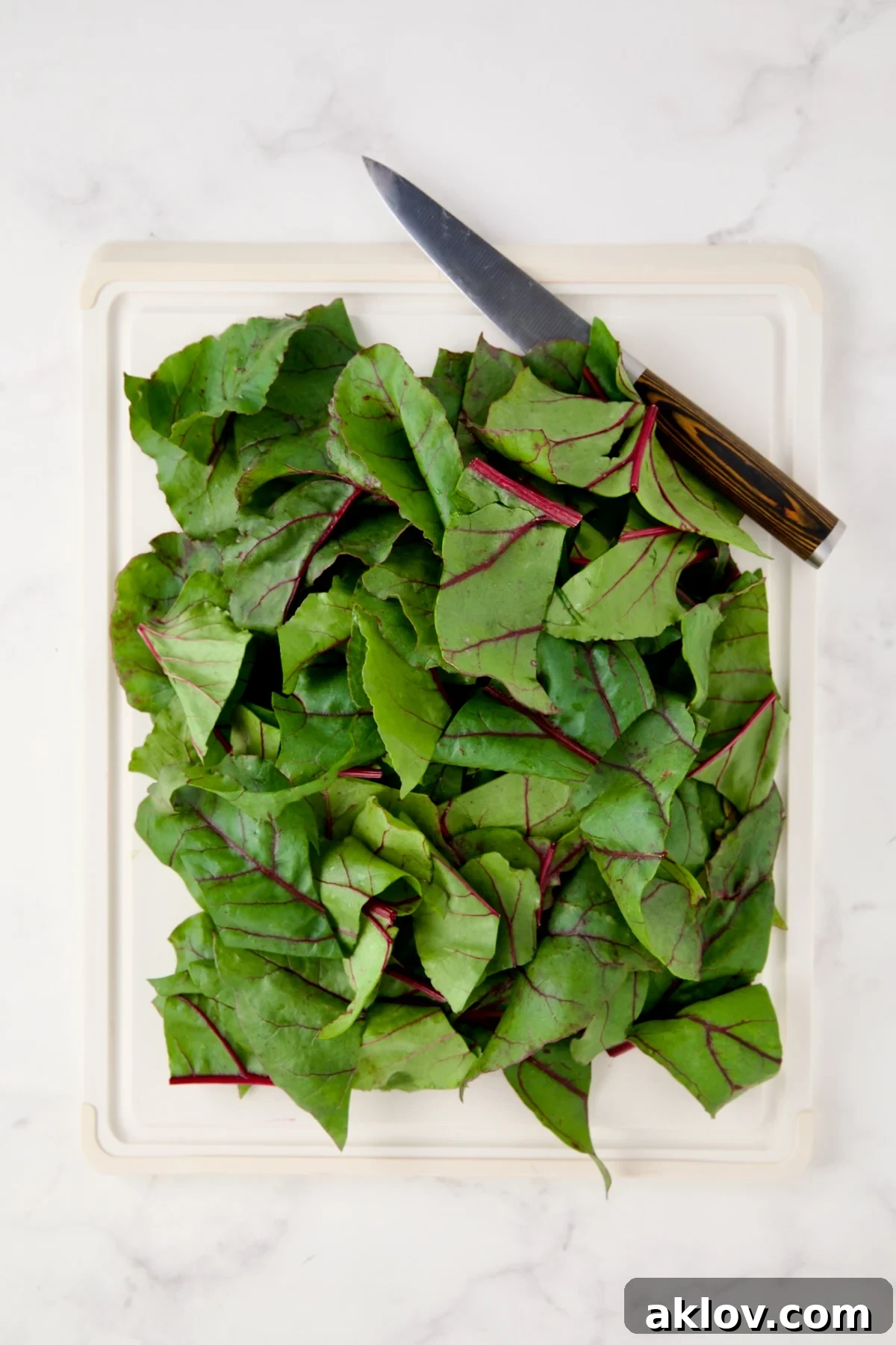 Coarsely chopped beet greens on white cutting board.