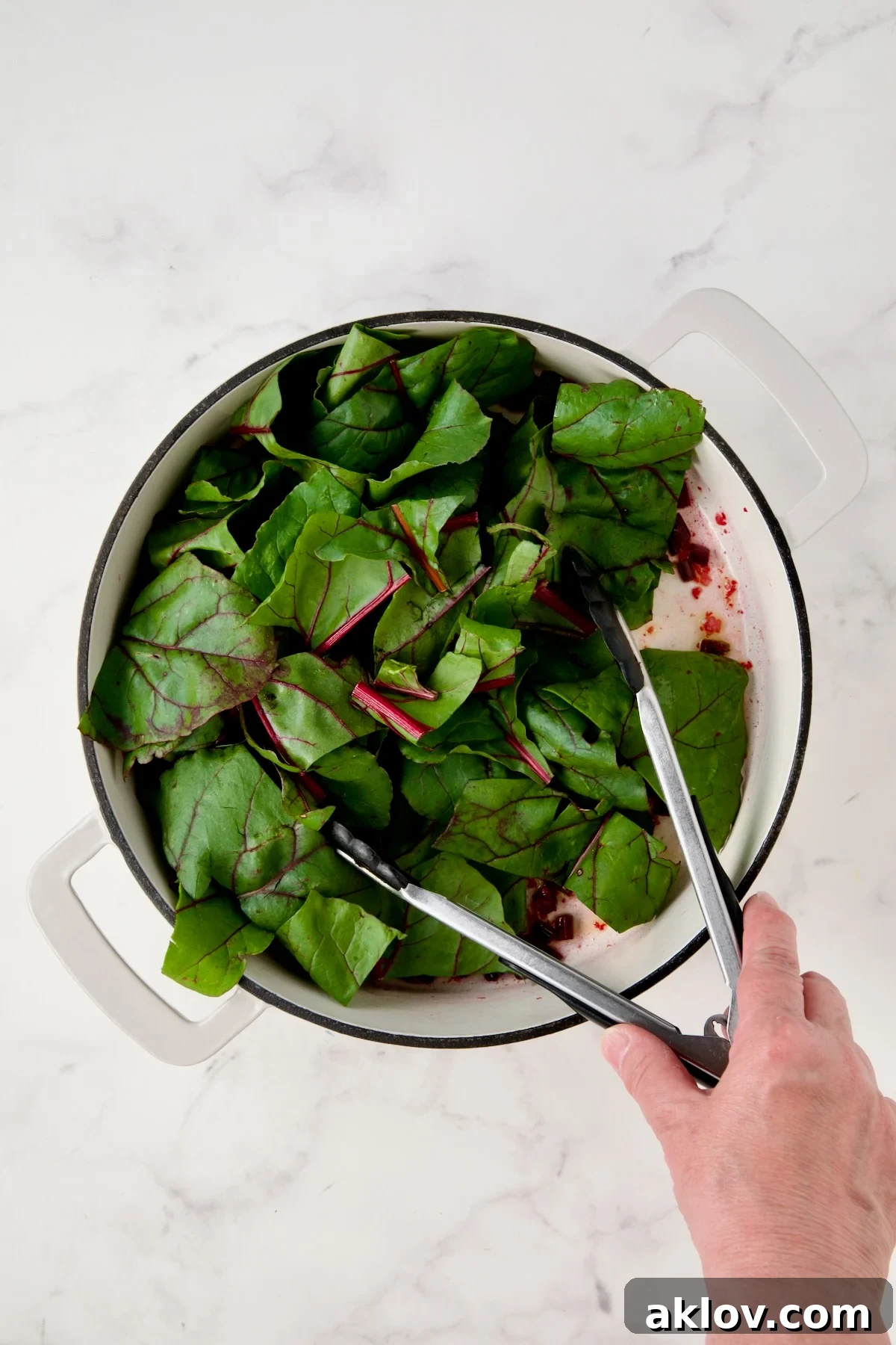 Coarsely chopped beet greens in white enamel cast iron skillet.