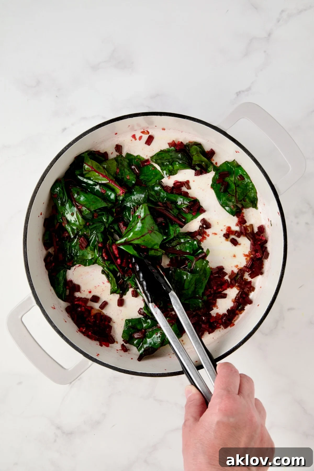 Wilted beet greens in white enamel cast iron skillet.