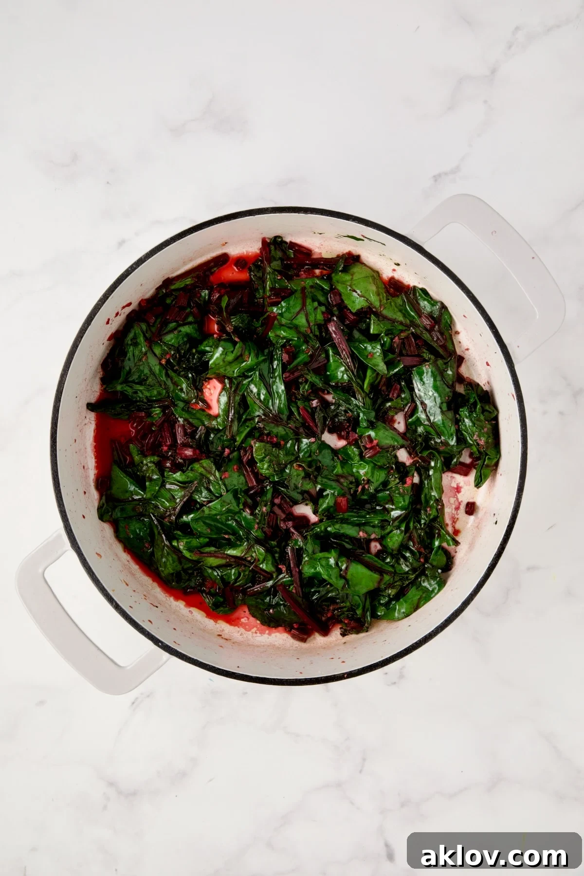Cooked beet greens in white enamel cast iron skillet.