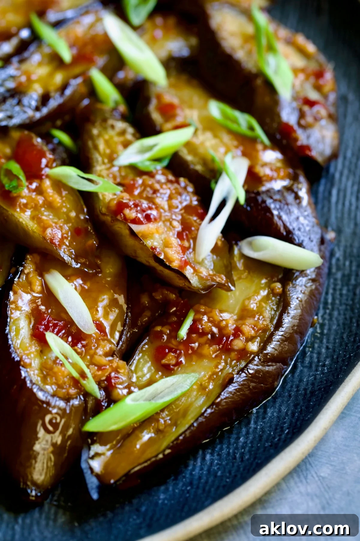 Thai Sweet Chili Glazed Eggplant Recipe 3 Thai Sweet Chili Eggplant on blue oval plate garnished with scallions.
