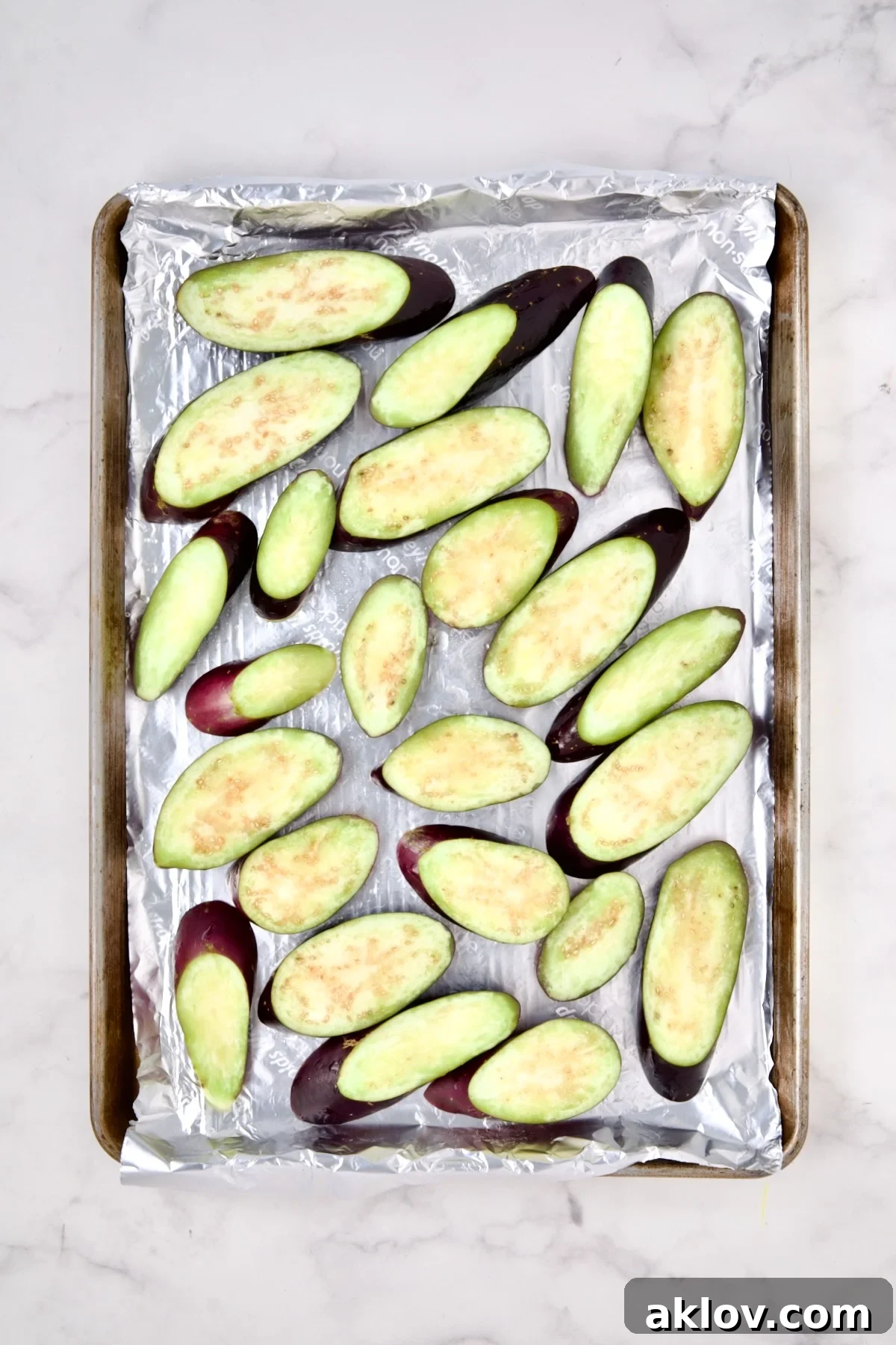 Thai Sweet Chili Glazed Eggplant Recipe 5 Sliced eggplant on aluminum-foil lined rimmed sheet pan before being baked.
