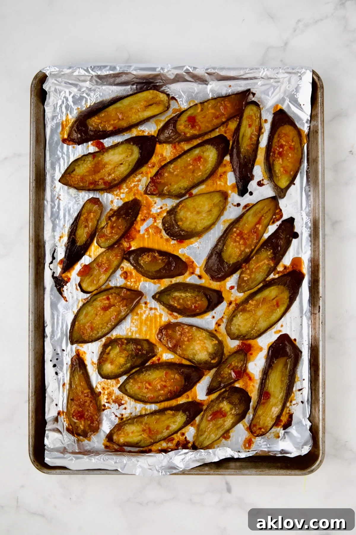 Thai Sweet Chili Glazed Eggplant Recipe 7 Sliced eggplant on aluminum-foil lined rimmed sheet pan after being broiled.