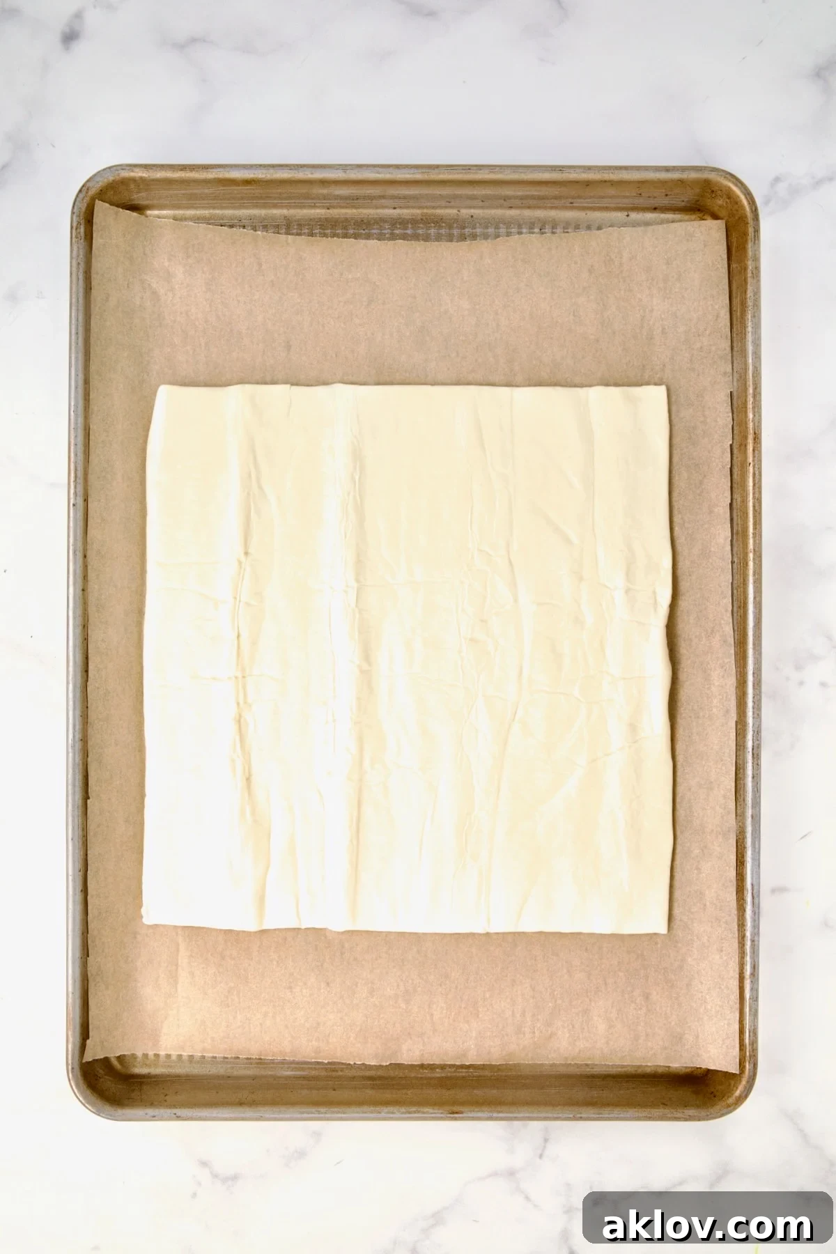 Puff pastry piece on parchment paper-lined rimmed baking sheet.