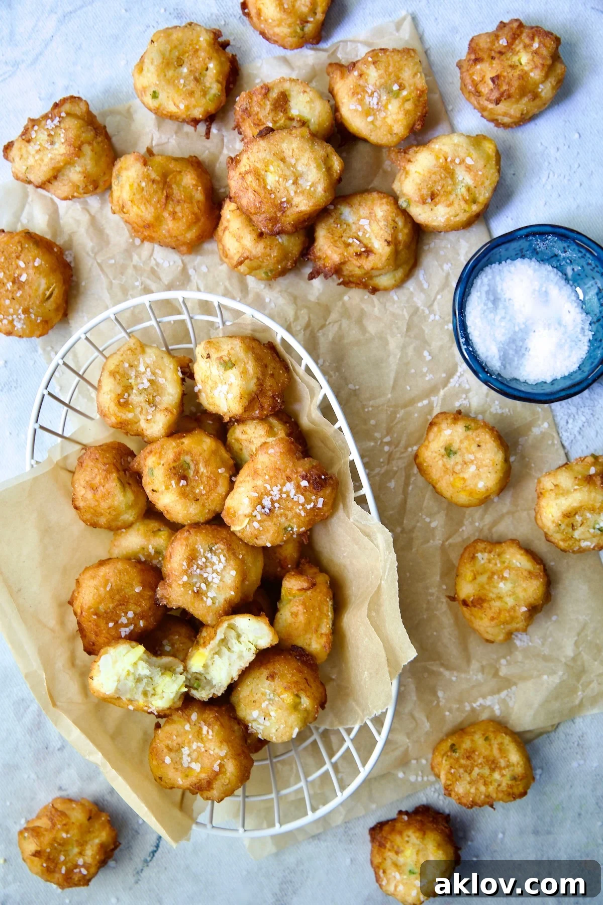 Squash Puppies on parchment paper and in white wire basket with dish of salt.