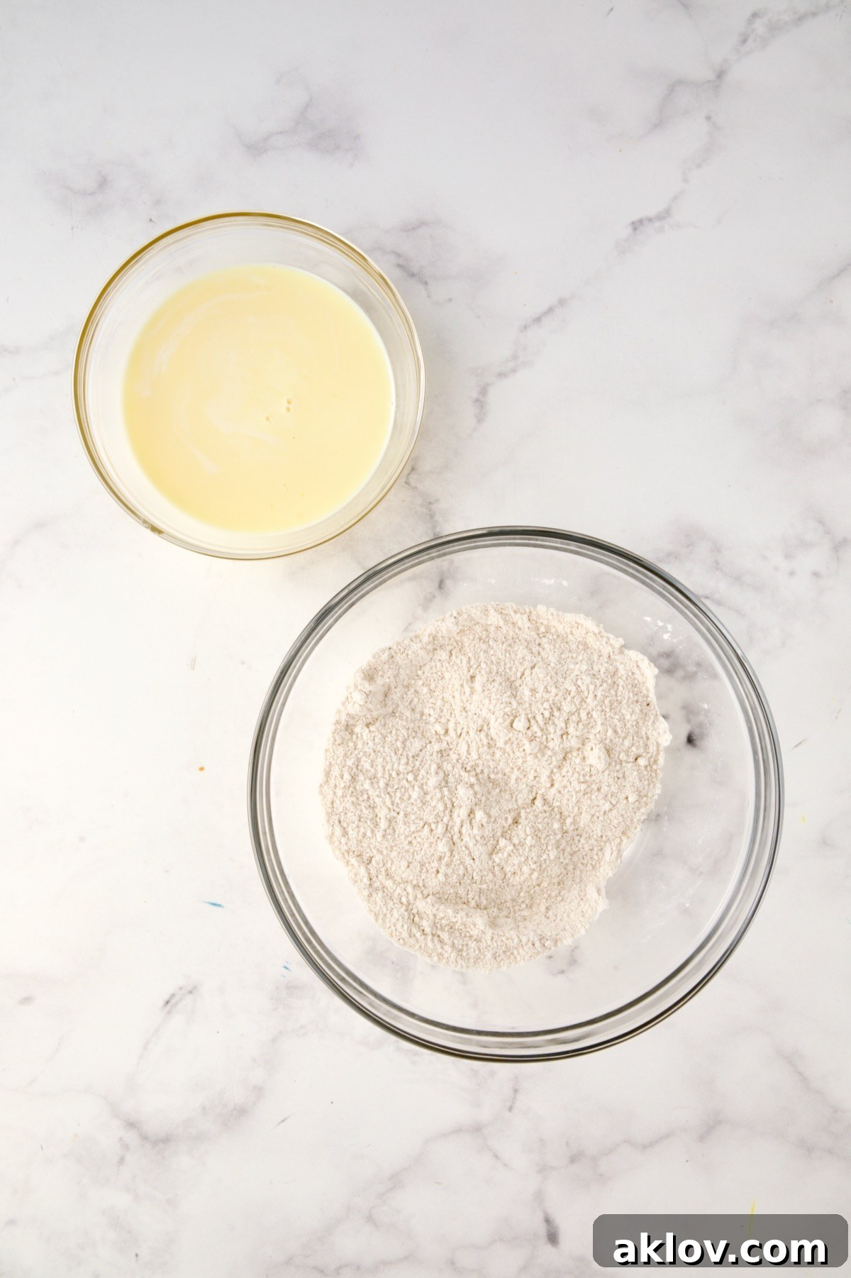 Two glass bowls with buttermilk and egg mixed together in one and cornmeal mix, flour and seasoned salt mixed together in another.