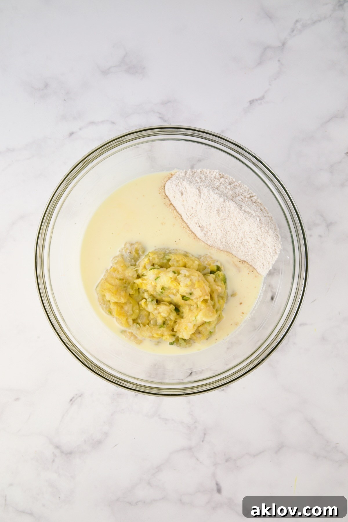 Mashed yellow squash mixture, buttermilk and egg mixture and cornmeal and flour mixture in glass bowl before being mixed together.